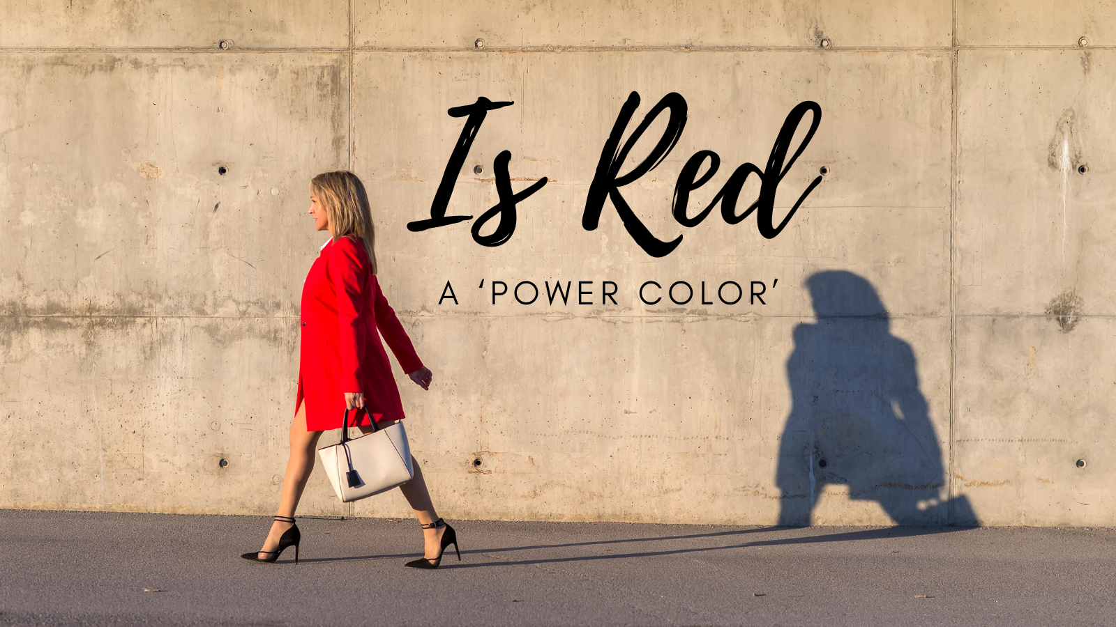 Woman in red coat walking past a concrete wall, with the words "Is Red a Power Color" overlaid